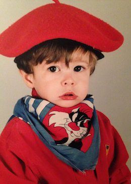 A young Jean-François wearing a red pullover shirt and beret